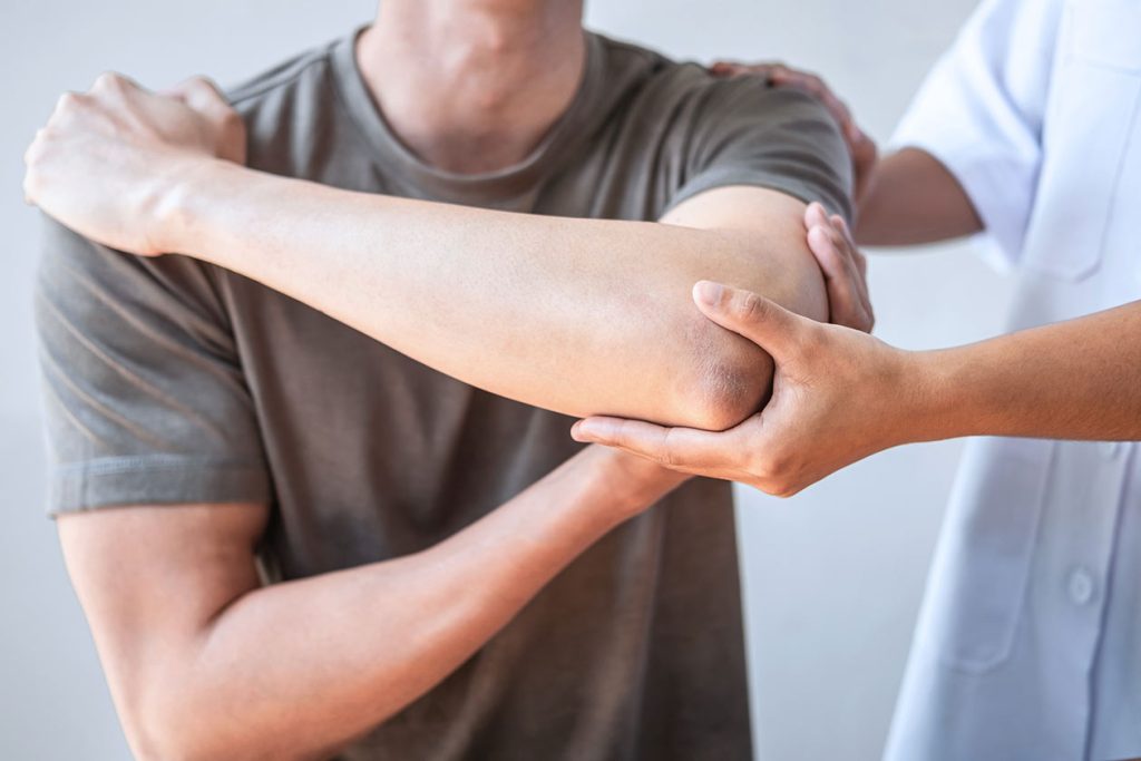 Young man and nurse holding his elbow up. Stem cell therapy for muscle injuries.